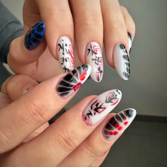 Nail art z czerwono-czarnymi wzorami i ilustracjami